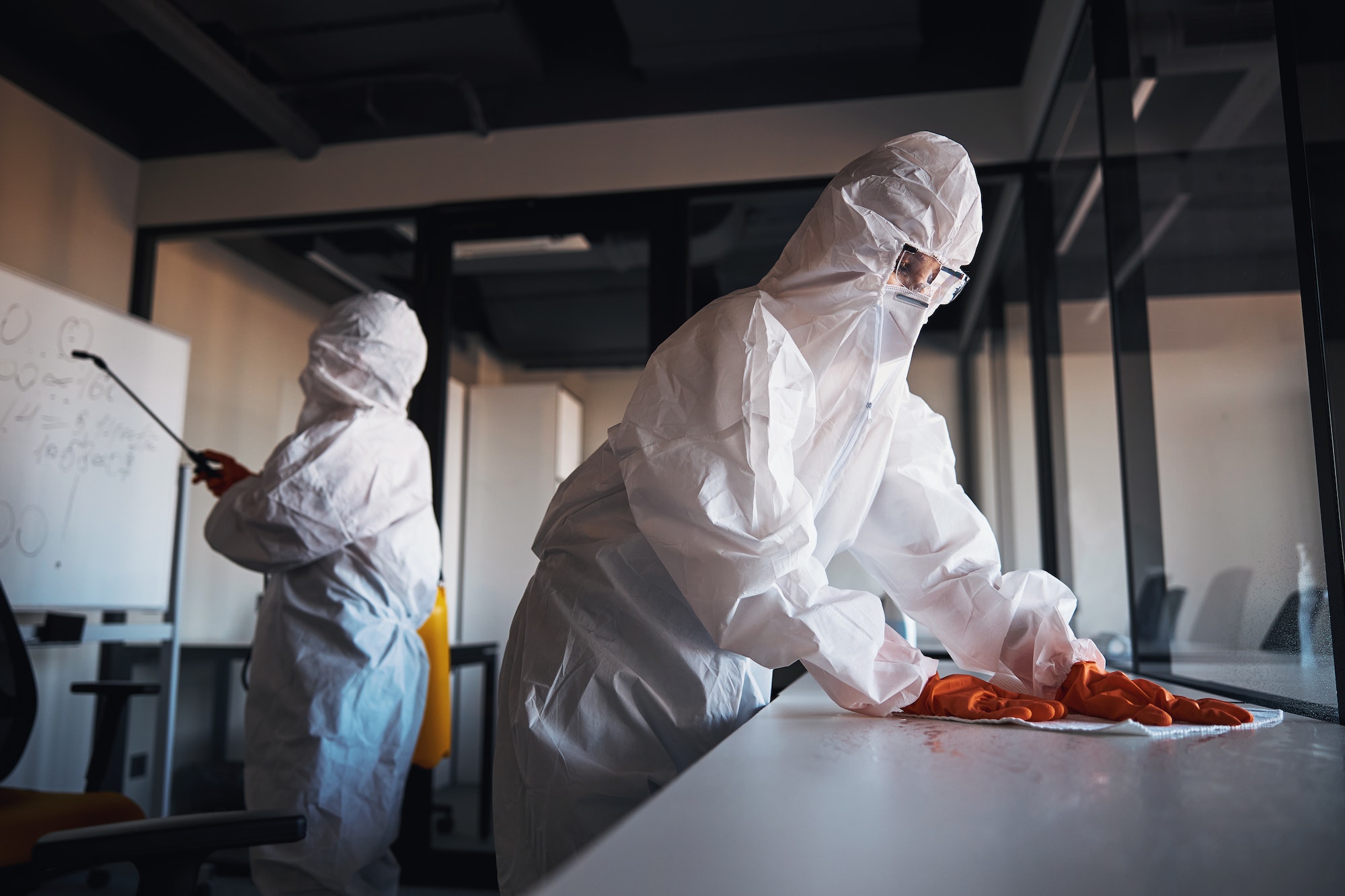 Cleaning staff in protective gear disinfecting the office workplaces